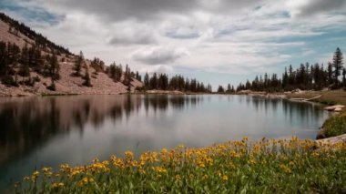 A time-lapse of clouds passing over Johnson Lake, an alpine lake in the Snake Range, located inside Great Basin National Park in Nevada, as seen on a summer day. Yellow flowers line the lakeshore.