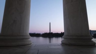 The Washington Monument and White House are seen from across the Tidal Basin, framed by two columns in the Jefferson Memorial. Sunrise time-lapse on a summer morning in Washington, DC.