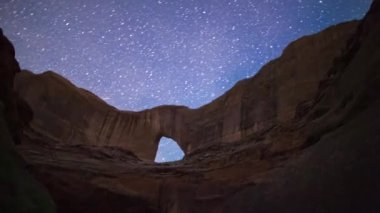 Stevens Doğal Kemeri 'nin hızlandırılmış hali, dünyanın en büyüklerinden biri, arka planda yıldızlı bir gece gökyüzü var. Escalante Nehri ve Stevens Canyon Kane County, Utah kavşağında yer alıyor..
