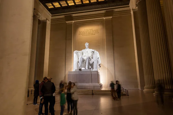 一个冬夜 游客们参观了华盛顿特区的林肯纪念堂 长时间的曝光表明 在亚伯拉罕 林肯总统令人印象深刻的雕像下 坐在椅子上的人模糊不清 — 图库照片
