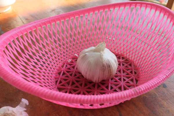 Bunch of garlic in a pink basket. Vitamin healthy food spice image. Spicy cooking ingredient picture. Pile of white garlic heads. White garlic head heap top view