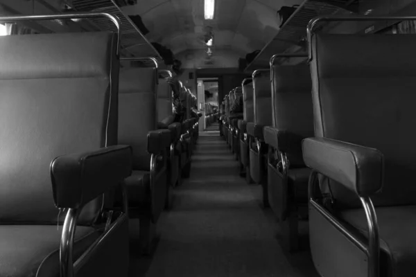 Passenger seats on Indonesian trains with people sitting on them. Black and White