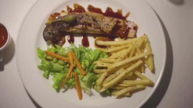 Kızarmış somon bifteği, üzerine patates kızartması ve sebze sosu, sağlıklı bir tarz.