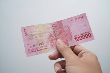 Hand holding one hundred thousand rupiah note isolated on white background. Indonesian rupiah currency