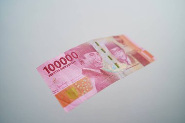 One hundred thousand rupiah falling on a white background