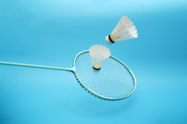 Two badminton shuttlecock and badminton racket on blue background