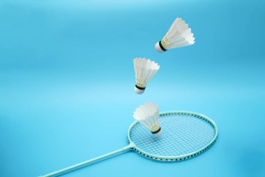 Badminton shuttlecocks and badminton racket on blue background
