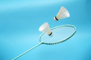 Badminton shuttlecocks and badminton racket on blue background