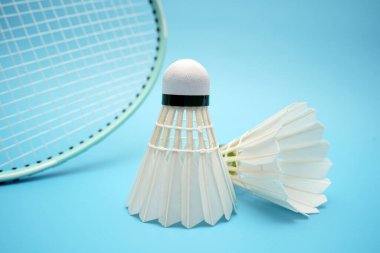 Badminton shuttlecock and badminton racket on blue background