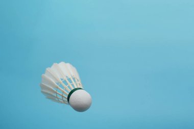 Badminton shuttlecock flying on blue background