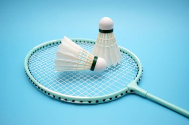 Badminton shuttlecock and badminton racket on blue background