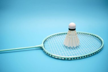 Badminton shuttlecock and badminton racket on blue background