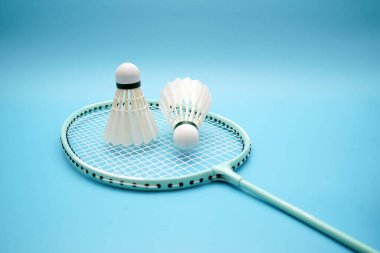 Badminton shuttlecock and badminton racket on blue background