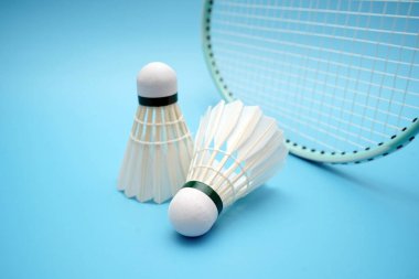 Badminton shuttlecock and badminton racket on blue background