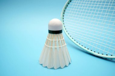 Badminton shuttlecock and badminton racket on blue background