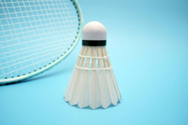 Badminton shuttlecock and badminton racket on blue background