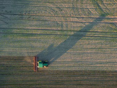 a farmer is harvesting the field with a tractor by summer sunset