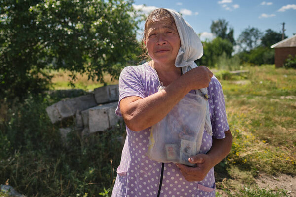 Tsirkuny, Kharkivska Oblast, July 1, 2022. A village woman praying for peace in a village freed from Russian occupation. She says her icons work as a bulletproof vest. 