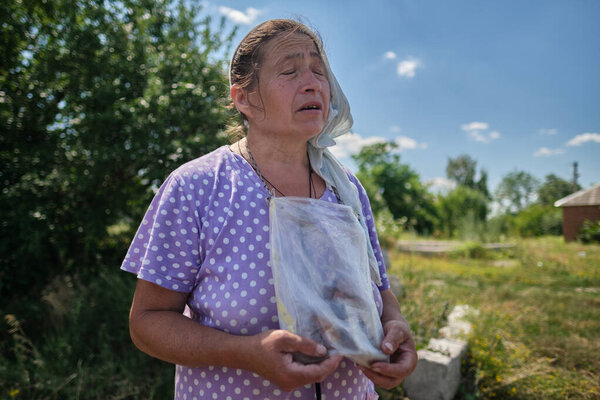 Tsirkuny, Kharkivska Oblast, July 1, 2022. A village woman praying for peace in a village freed from Russian occupation. She says her icons work as a bulletproof vest. 