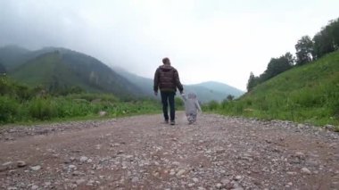 Baba ve oğlu dağların yakınında yürüyorlar. Yüksek kalite 4k görüntü