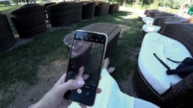 İş kadını akıllı telefonuyla fotoğraf çekiyor ve gün batımında oturuyor. Yüksek kalite 4k görüntü