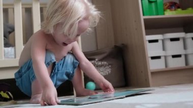 Küçük çocuk yerde oturmuş kitap okuyor. Yüksek kalite 4k görüntü