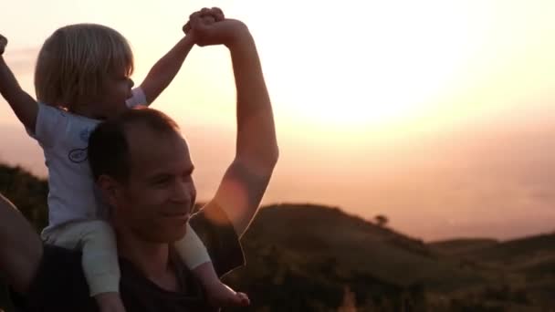 Gün Batımında Dağlarda Omuzlarında Sevimli Bir Oğlu Olan Baba Kameraya — Stok video