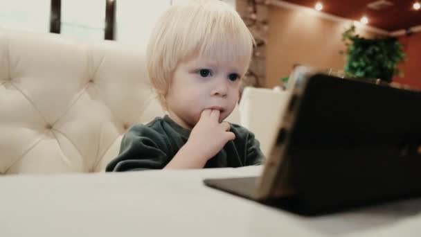 Милый Маленький Мальчик Смотрит Видео Смартфоне Сидя Кафе Высококачественные Кадры — стоковое видео