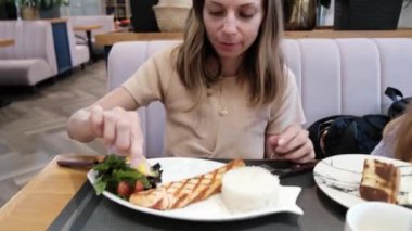 Güzel bir kadın bir kafede oturur ve yemeğin içine limon sıkıştırır. Yüksek kalite 4k görüntü