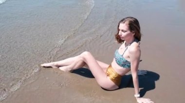 Genç ve güzel bir kadın deniz kıyısında güneşlenir. Yüksek kalite 4k görüntü