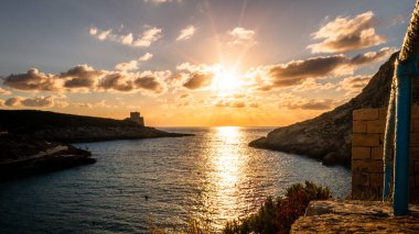Gozo, Malta 'da günbatımı. Gün batımında bulutlu gökyüzüne uzan. Alçak güneş, sıcak renkler. Akşamları güzel deniz manzarası.