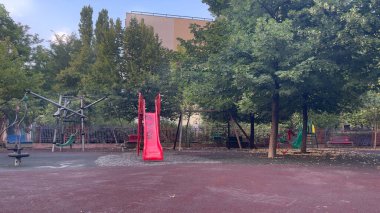 Kızıl çocuklar boş bir oyun bahçesinde yaz günü kayıyorlar.