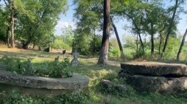 Terk edilmiş eski bir fıskiyenin yanındaki çayırda çapraz mezar taşı