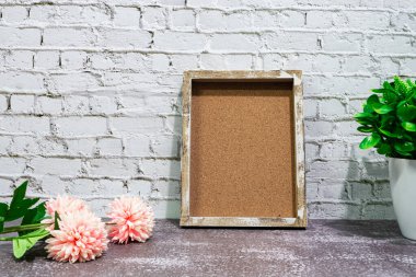 Wooden frame with potted plant and flowers on wooden background. Copy space.