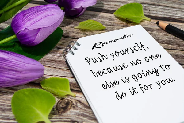 Motivational quote on notepad with flowers on wooden desk - Remember, push yourself, because no one else is going to do it for you.