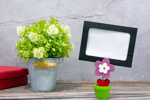 Paper frame with potted plant and books on wooden background. Copy space.