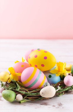 Ahşap arka planda yuvada çok renkli paskalya yumurtaları. Mutlu Paskalya tebrik kartları. Paskalya arkaplanı.