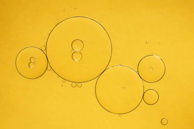 Altın sarısı soyut yağ kabarcıkları ya da yüz serumu arka planı. Petrol ve su baloncukları makro fotoğrafçılık.