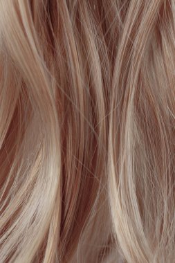 Brown curly hair texture closeup. Light brown hair background.