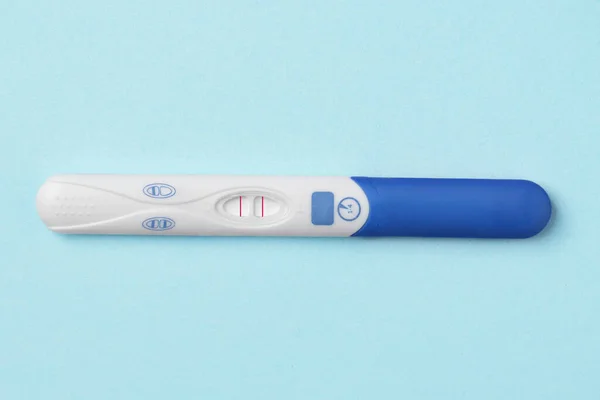 Blue positive pregnancy test on blue background. Positive result of pregnancy test.