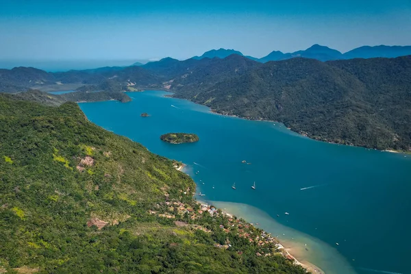 Mavi suyu ve yatları olan, tropikal bir ormanı ve havadan manzarası olan bir göl.