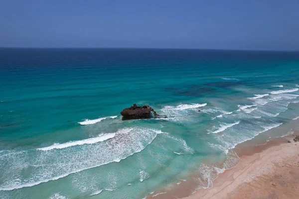 Okyanusta batık bir gemi kumsalın yanında, drone manzaralı.