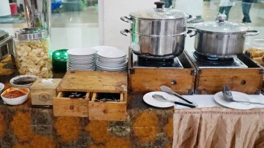 pile of bowls beside pots of hot sauce on the buffet table