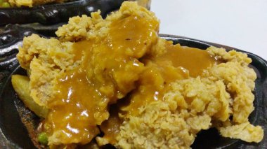 Sıcak tabakta servis edilen barbekü soslu çıtır tavuk bifteğini yakın.