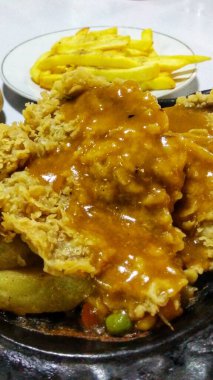 Sıcak tabakta servis edilen barbekü soslu çıtır tavuk bifteğini yakın.