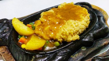 Izgara tavuk bifteği, barbekü sosu ve sebze soteli fırında servis edilir.