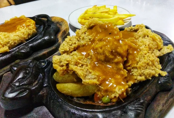 Sıcak tabakta servis edilen barbekü soslu çıtır tavuk bifteğini yakın.