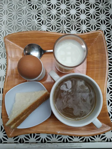 a cup of coffee with milk and a glass of tea on a wooden table