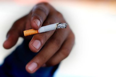 Elinde sigara tutan bir adama yaklaş.