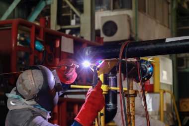 Koruyucu maskeli kaynakçı çelik kaynak yapıyor.
